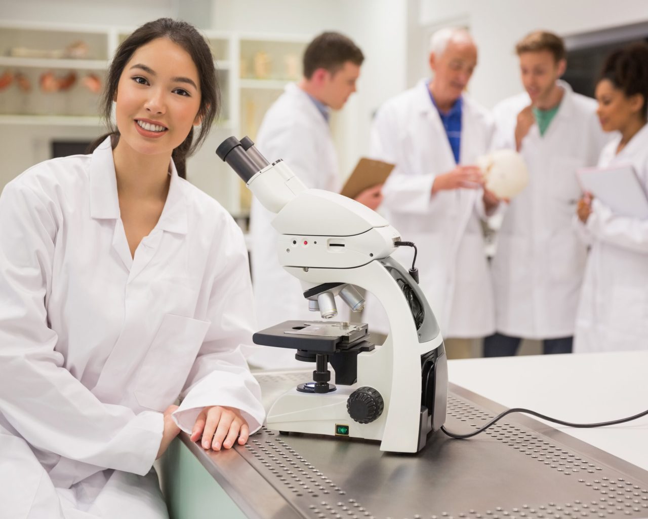 Young medical student working with microscope at the university